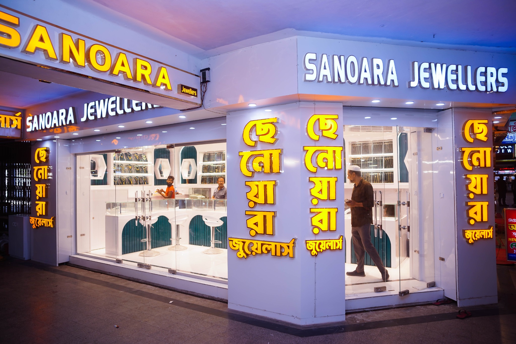 Sanowara Jewellers at Biponi Bitan, Chittagong, with illuminated signage, glass frontage, white counters, and teal display details